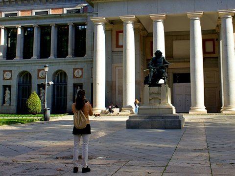 a woman taking a picture of a statue in front of a building