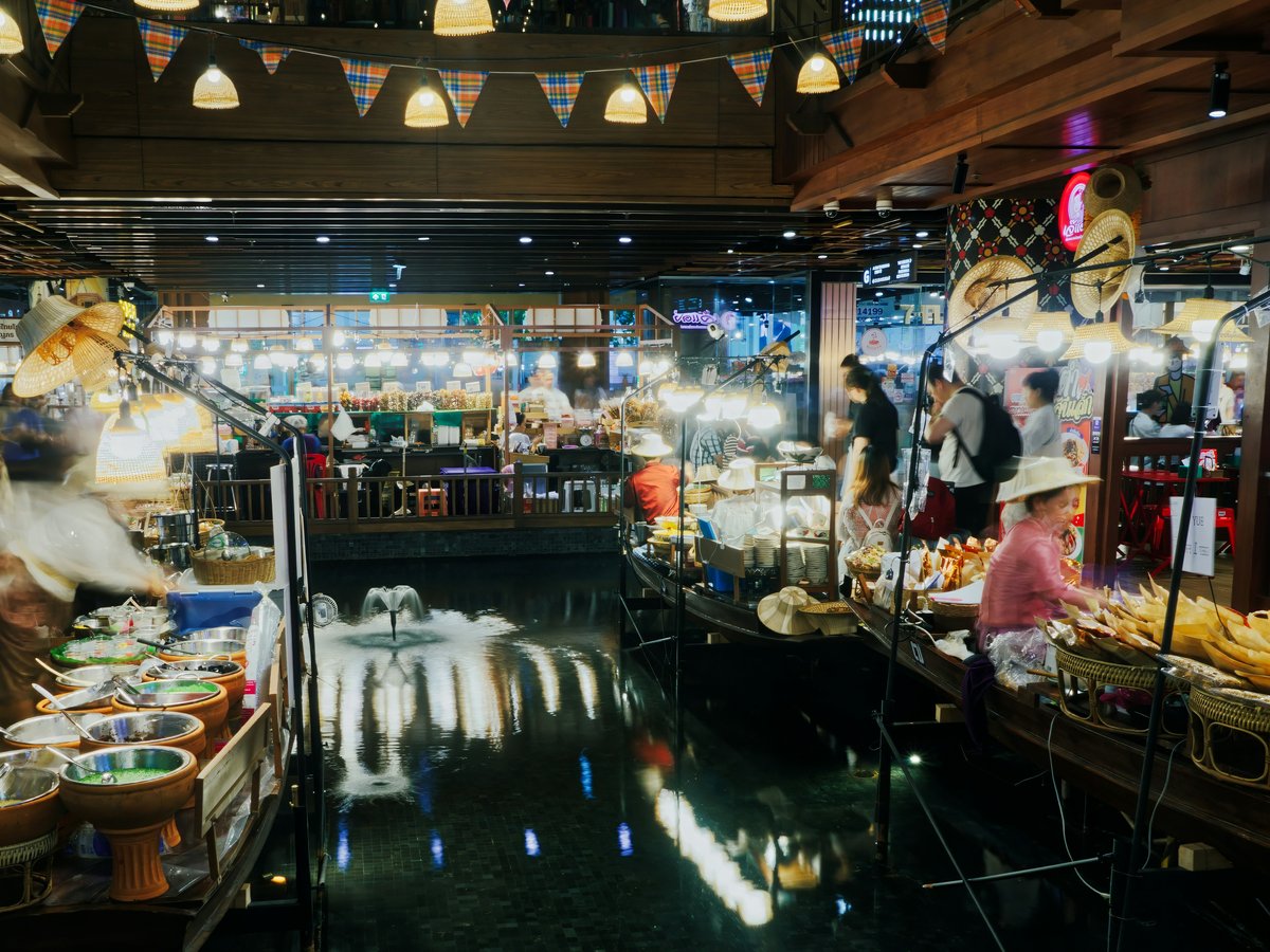 People shopping at a bustling floating market at night.