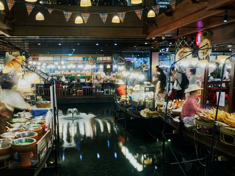 People shopping at a bustling floating market at night.