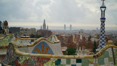 The serpentine trencadís bench at Park Güell, its hand-broken ceramic tiles in cobalt, ochre, and ivory snaking across a terrace that opens onto the Barcelona skyline