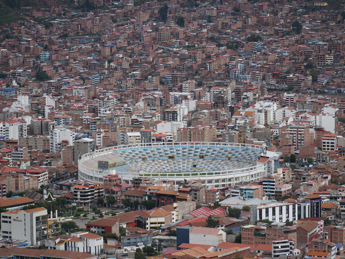 A modern stadium surrounded by dense city buildings.