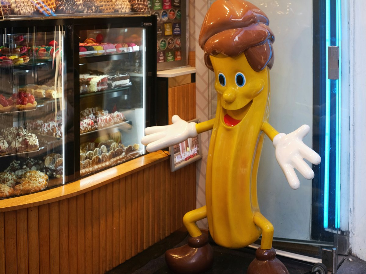 a large banana character standing in front of a bakery