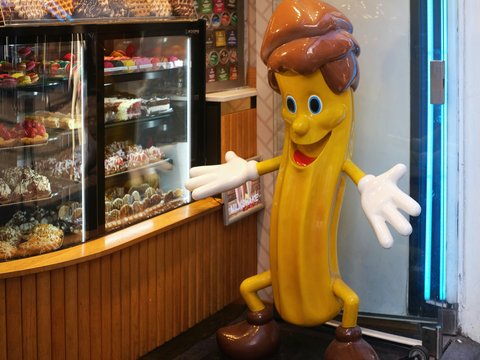 a large banana character standing in front of a bakery
