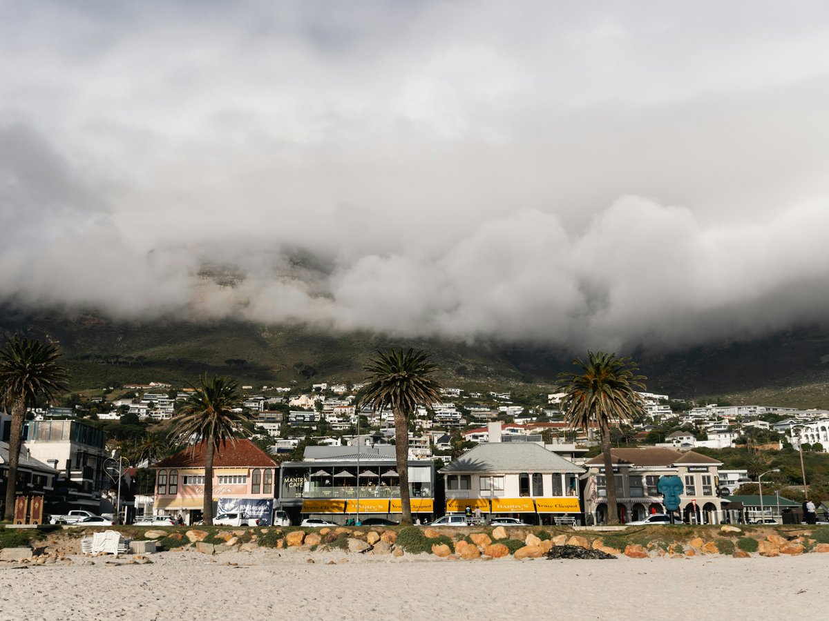 Beachside homes sit beneath a cloudy mountain.