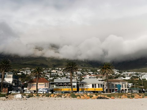 Beachside homes sit beneath a cloudy mountain.