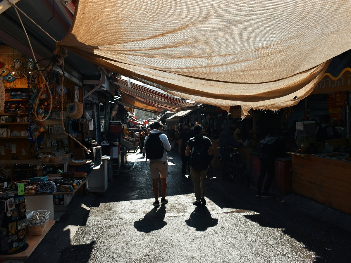 a group of people walking down a street next to a store