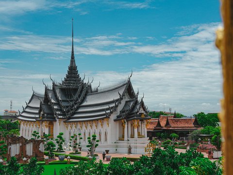 A beautiful thai temple stands under a blue sky.