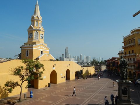 Yellow historic clock tower in a sunny plaza.