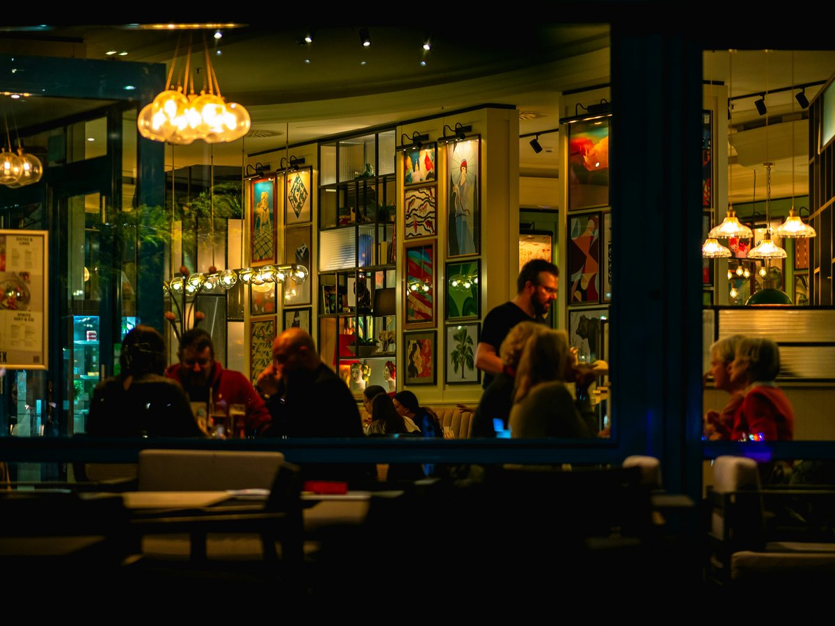 A group of people sitting outside of a restaurant at night