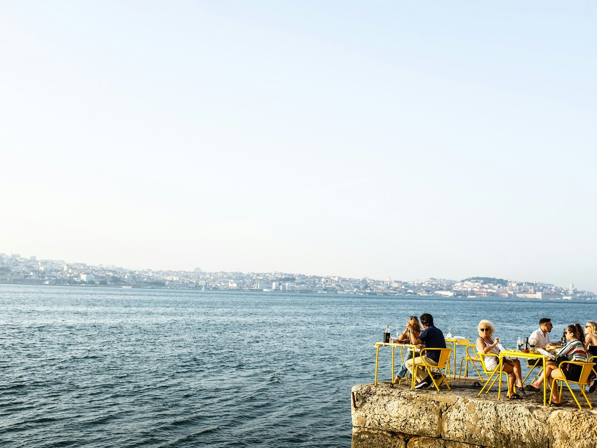 man and woman sitting on brown rock near body of water during daytime