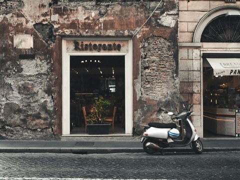 black and white motor scooter parked beside brown concrete building during daytime