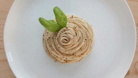 A steaming bowl of hand-rolled Roman pasta glossed in buttery sauce and cracked black pepper, rustic linen and a weathered trattoria table completing a warm, lived-in still life