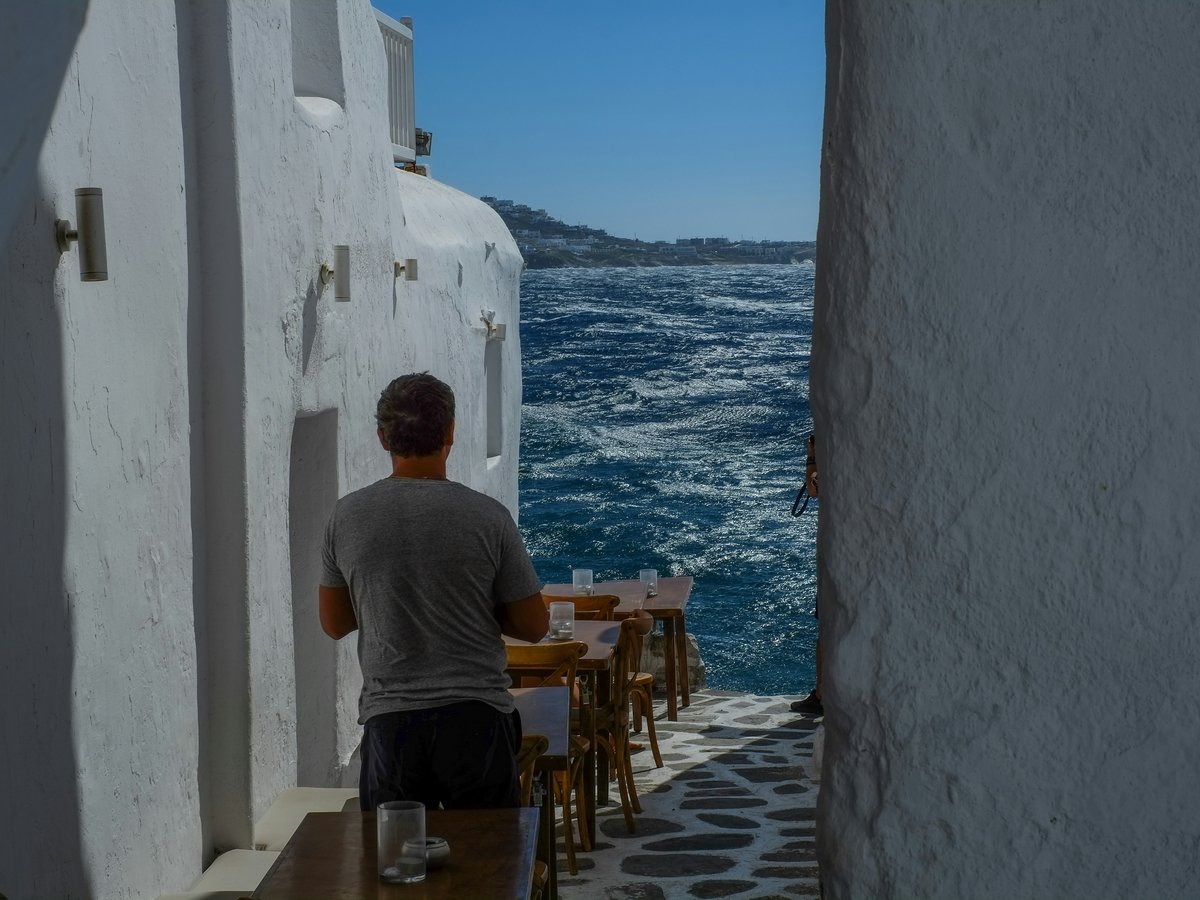man in gray crew neck t-shirt sitting on brown wooden chair during daytime