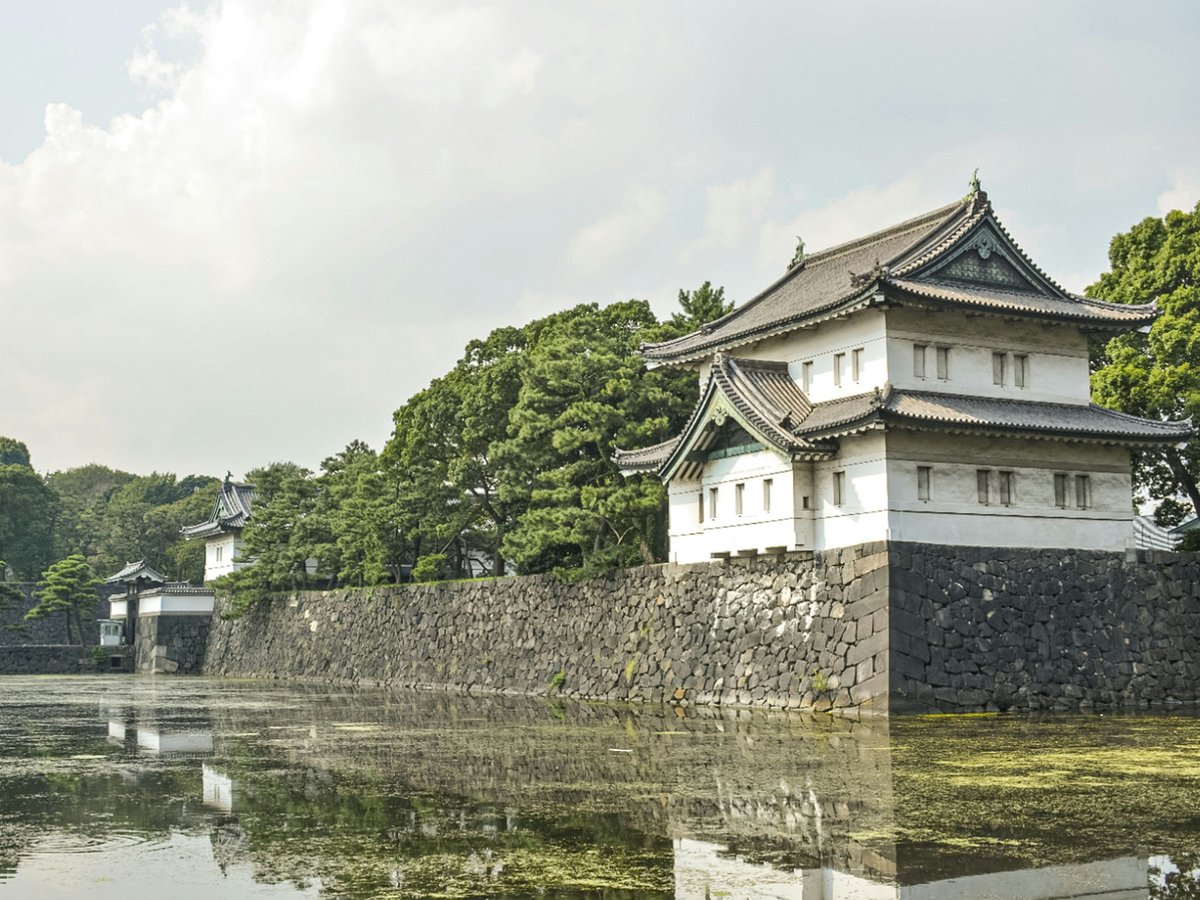 a building with a stone wall and trees in the background