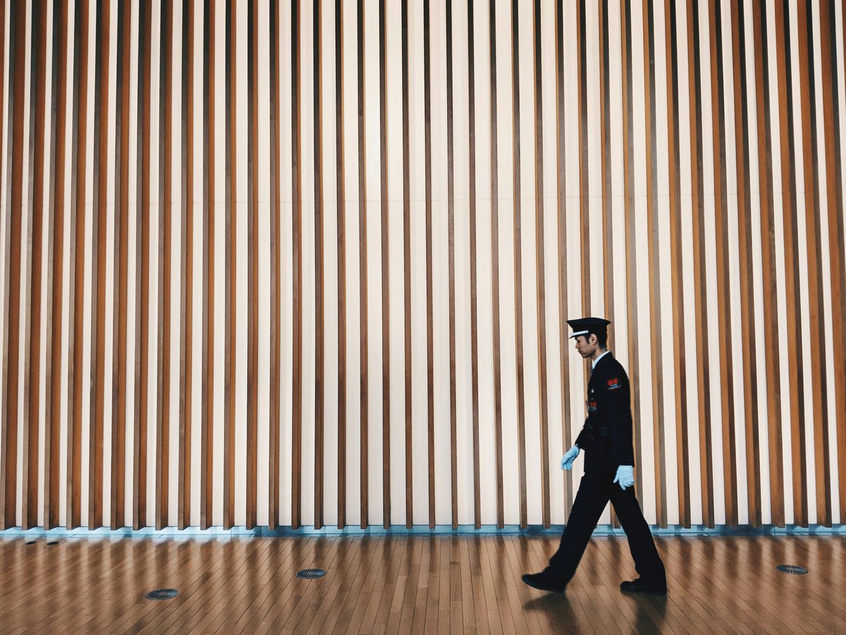 man in black coat and black pants standing on brown wooden floor