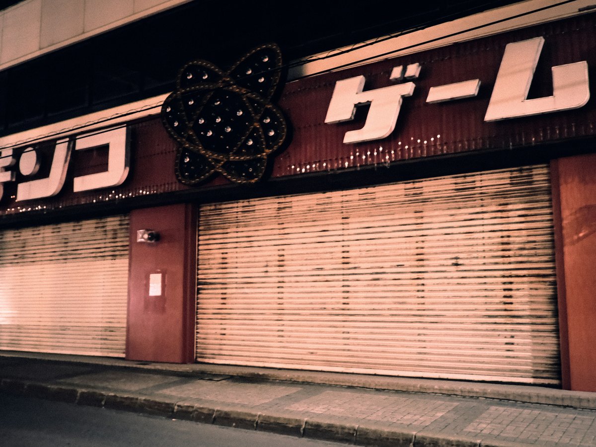 A closed pachinko parlor with metal shutters at night in Japan