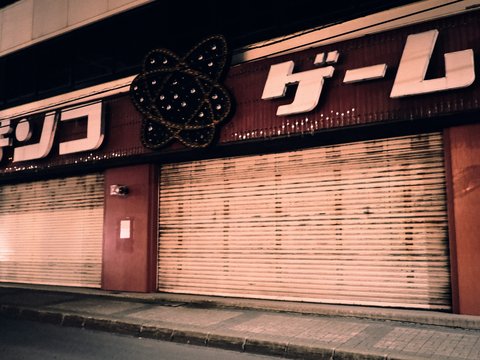 A closed pachinko parlor with metal shutters at night in Japan