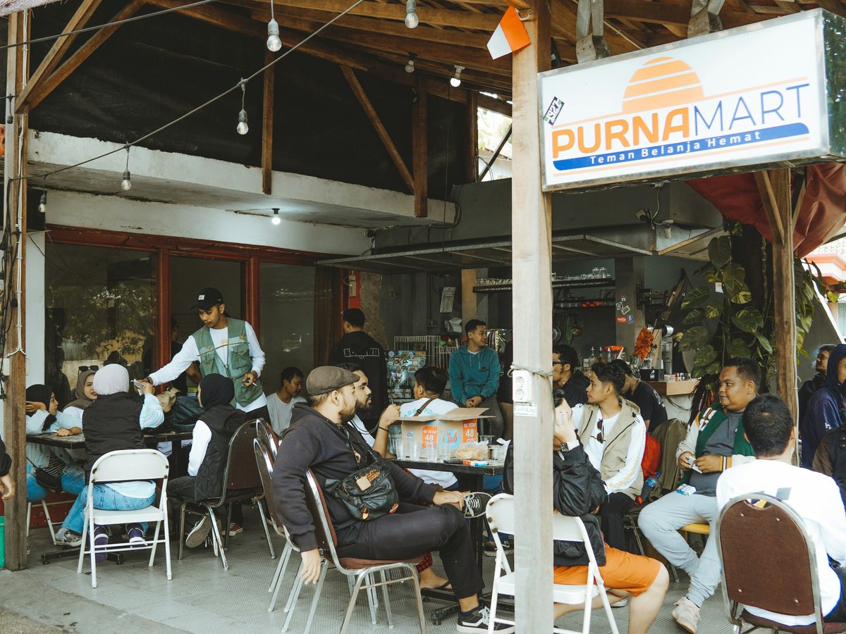 People socialize and eat outside a small cafe