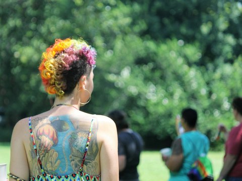 a woman with tattoos on her back standing in a park