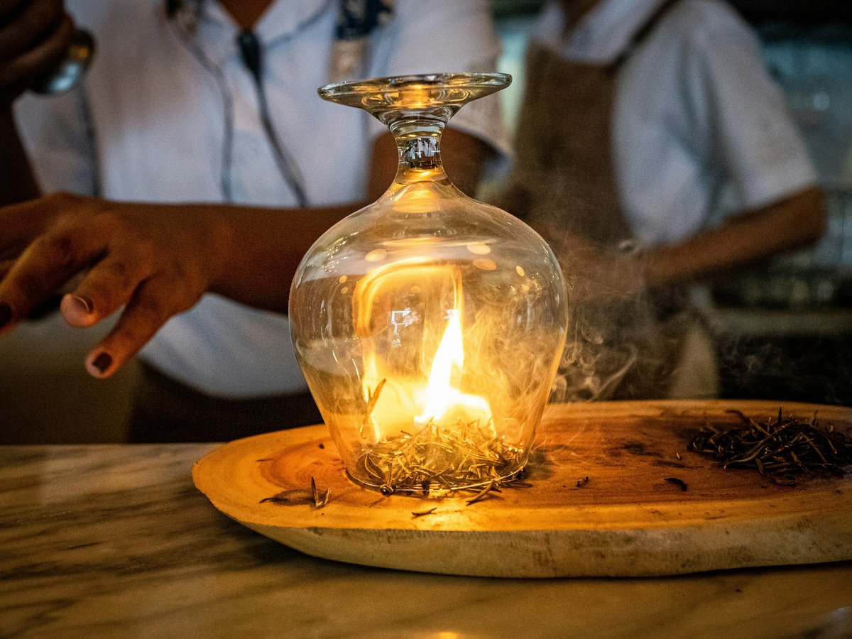 a person sitting at a table with a candle in a glass bottle