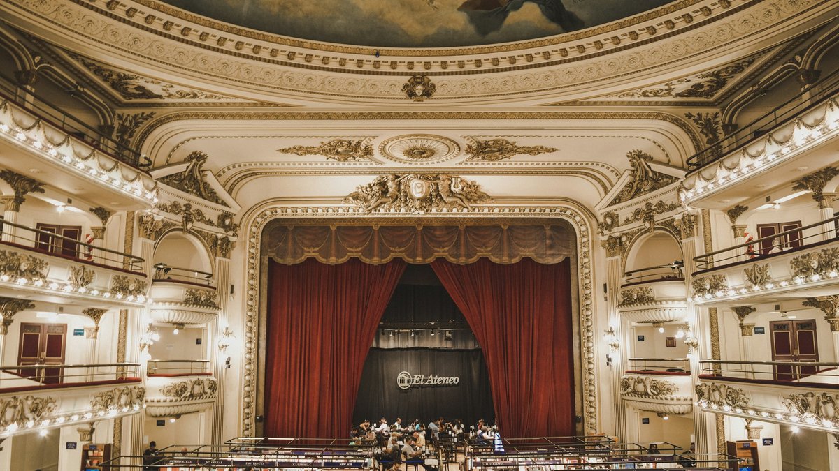 The El Ateneo Grand Splendid bookstore interior, crimson stage curtain framing the gilded Belle-Époque balconies and painted ceiling fresco arching above bookshelves that fill the former orchestra floor