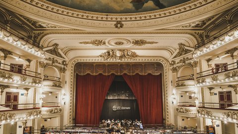 The El Ateneo Grand Splendid bookstore interior, crimson stage curtain framing the gilded Belle-Époque balconies and painted ceiling fresco arching above bookshelves that fill the former orchestra floor