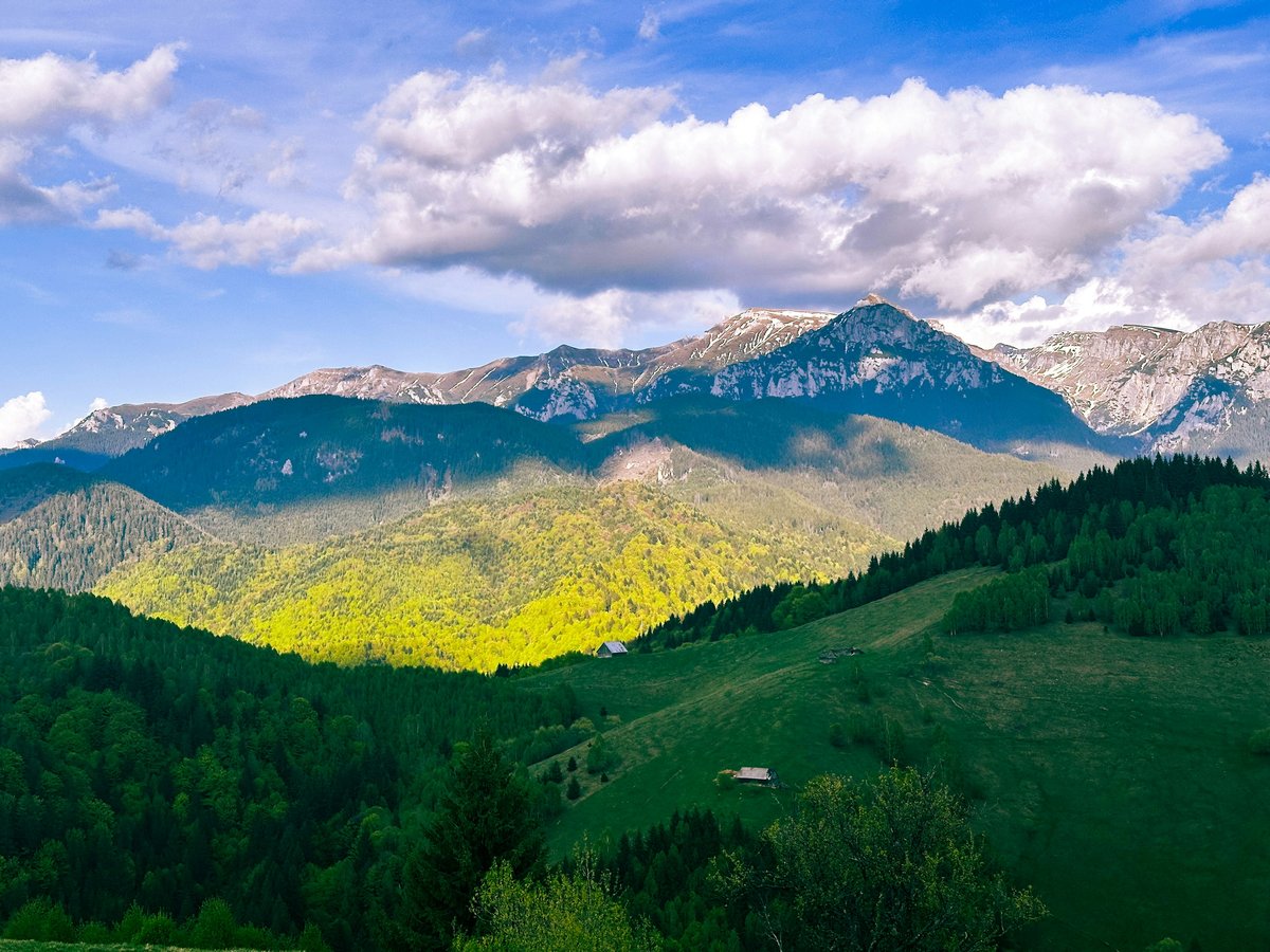 Green mountains and forests under a cloudy sky.