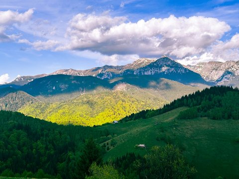 Green mountains and forests under a cloudy sky.