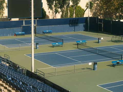 Empty tennis courts with blue seating and nets