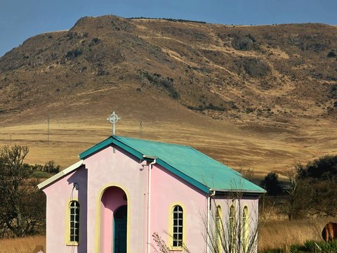 A pink church sits amidst a brown landscape.