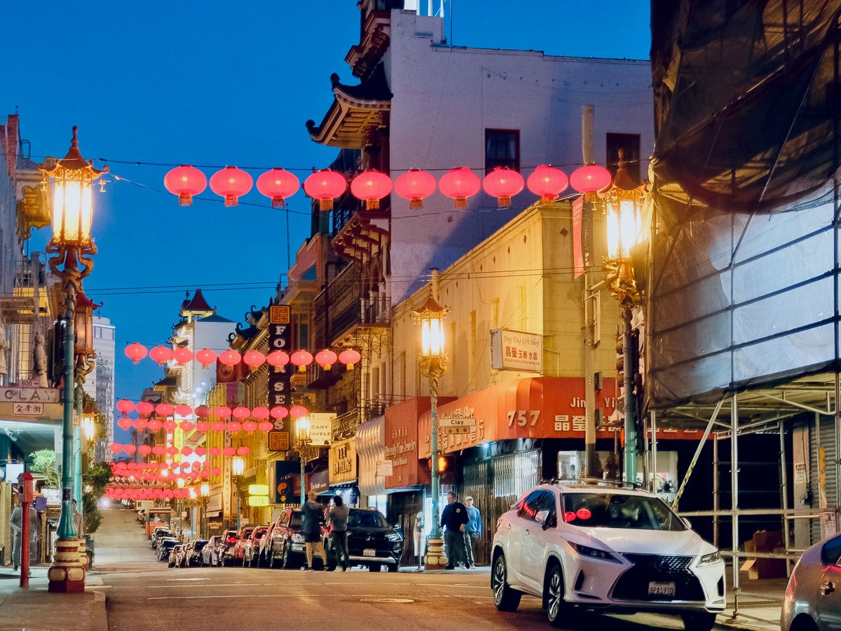 a street with cars and buildings with lanterns from the roof
