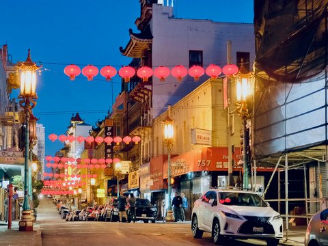 a street with cars and buildings with lanterns from the roof