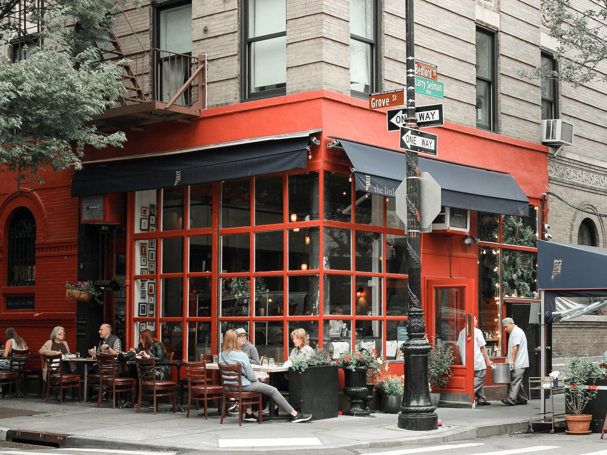 a group of people sitting at tables outside of a restaurant