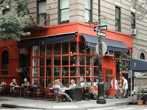 a group of people sitting at tables outside of a restaurant