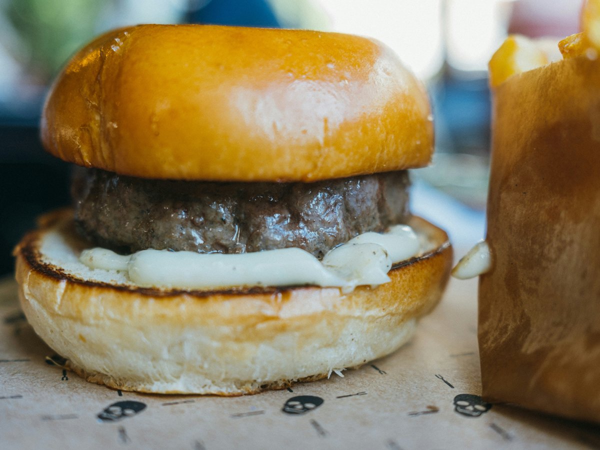 a hamburger sitting on top of a table next to a bag