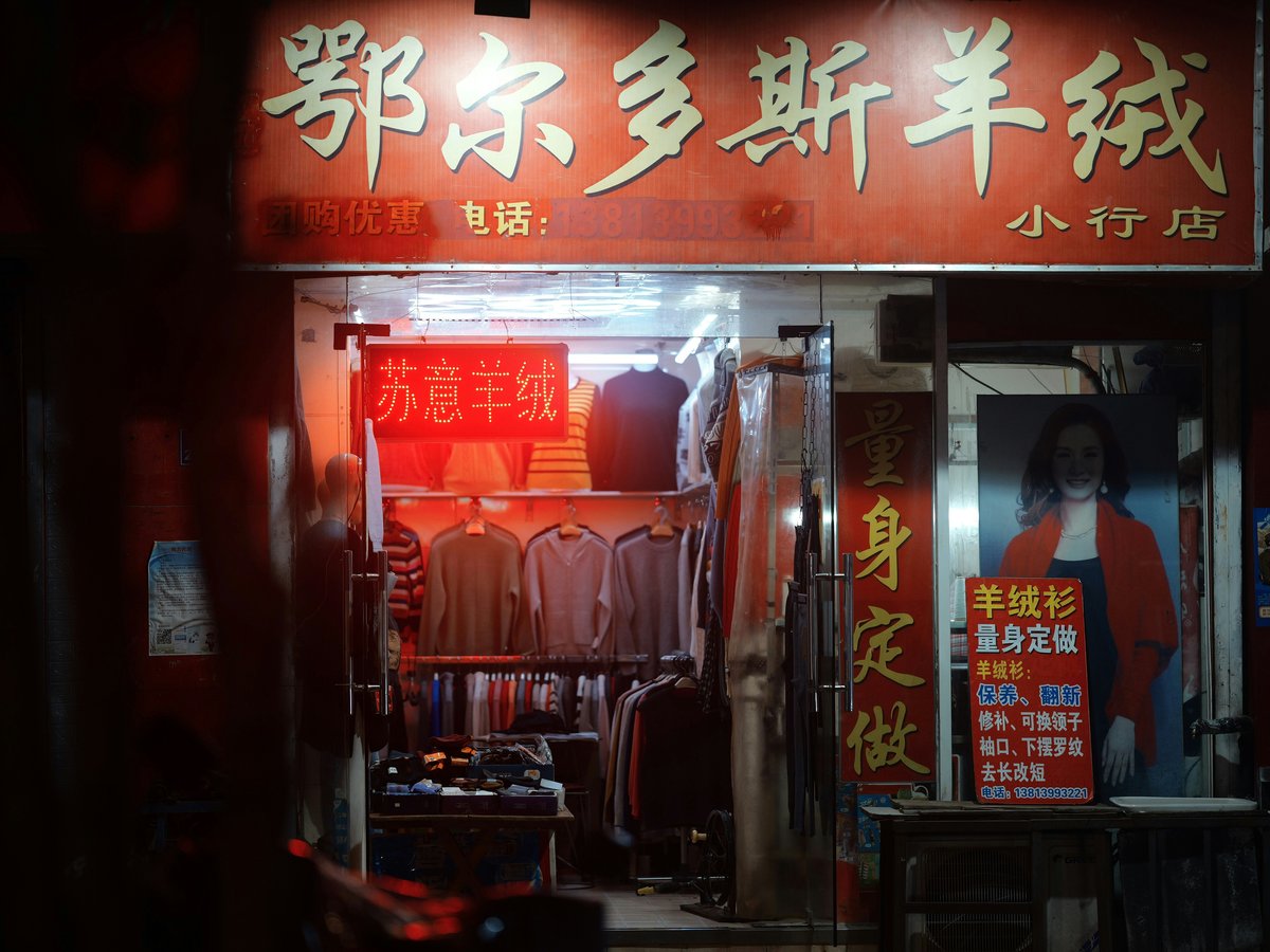 A storefront with chinese characters and clothing displays of clothing