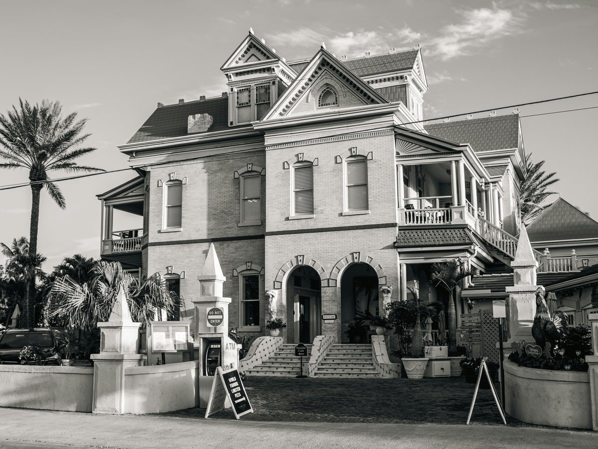 Historic victorian house with ornate details and palm trees.