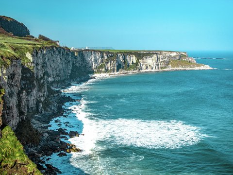 white rock cliff beside body of water'
