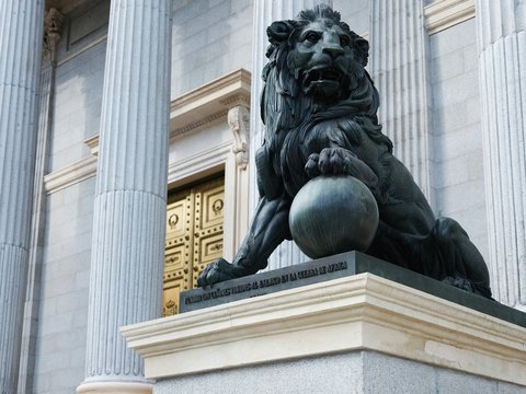 a statue of a lion holding a ball in front of a building