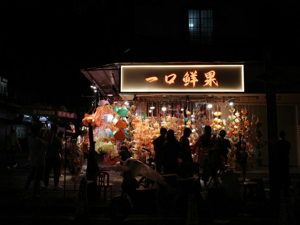 a group of people standing outside of a store at night