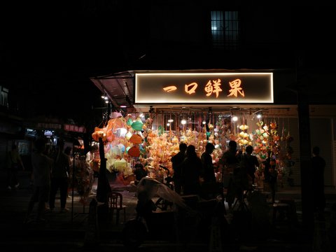 a group of people standing outside of a store at night