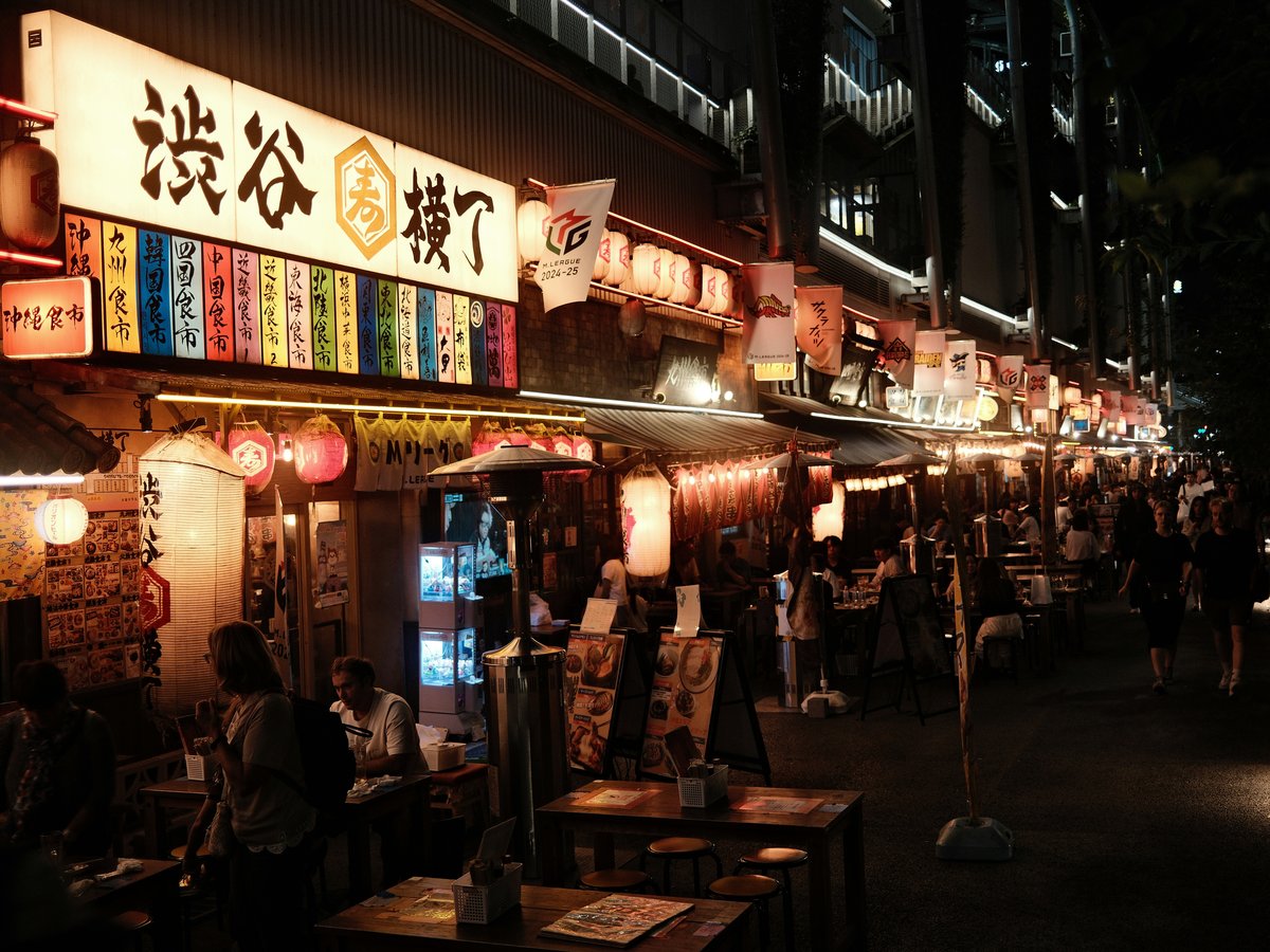 A group of people standing outside of a restaurant at night