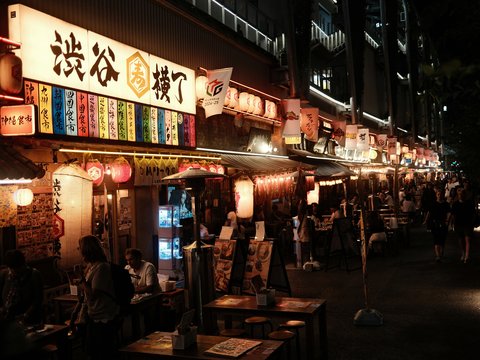 A group of people standing outside of a restaurant at night