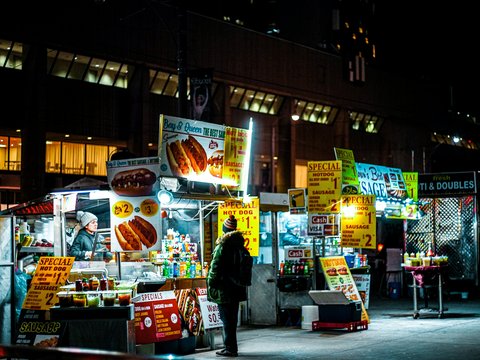 man in black jacket standing in front of store during nighttime