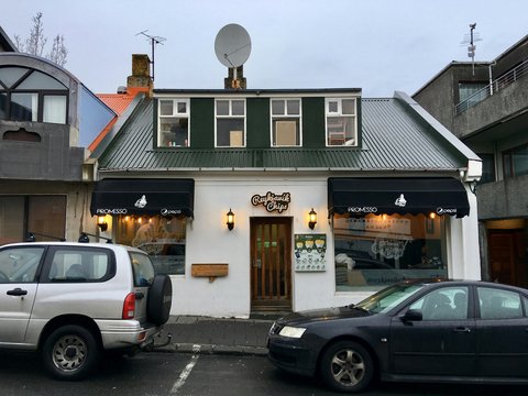 A small white building with black awnings and cars