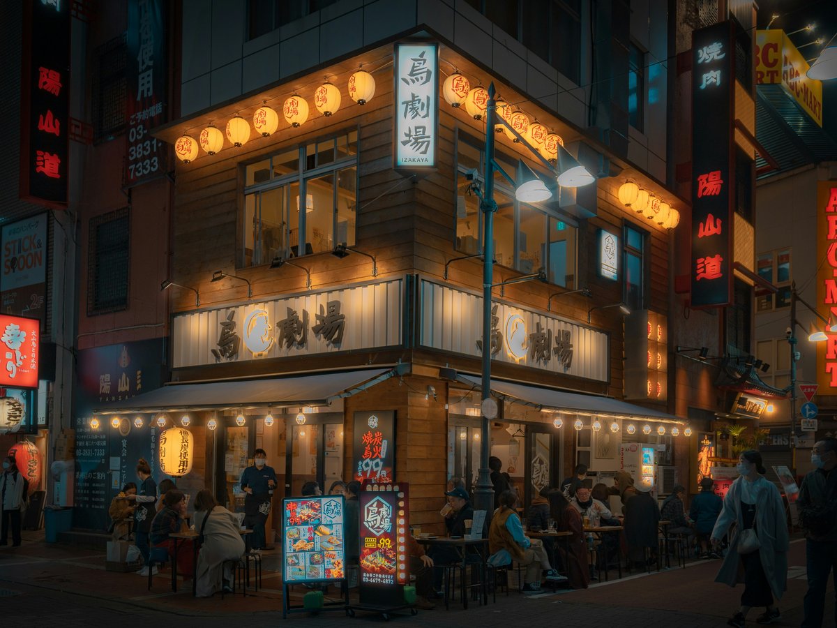 a group of people standing outside of a restaurant at night