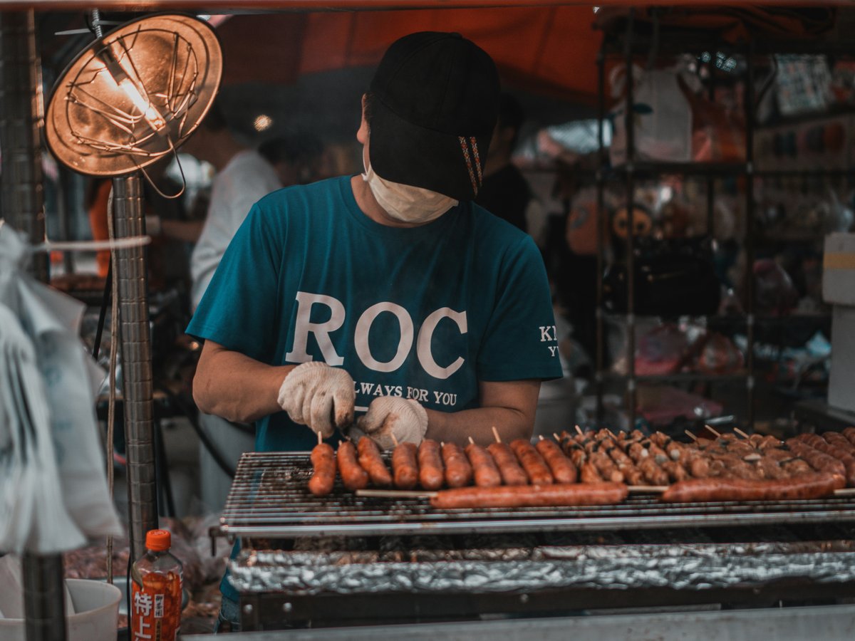 man in blue and white crew neck t-shirt standing in front of food stall