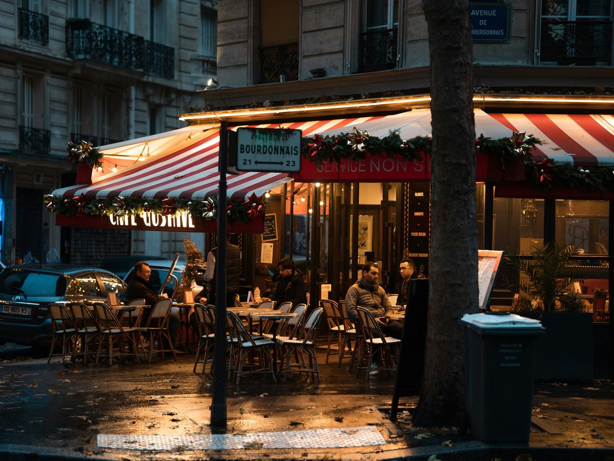 a group of people sitting at a table outside of a restaurant