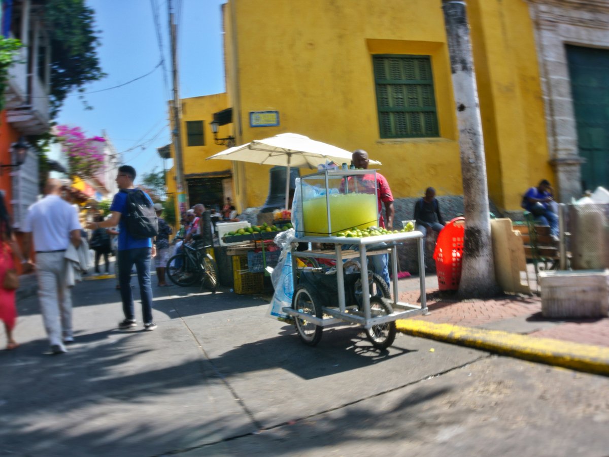 Street vendor selling drinks from a cart.