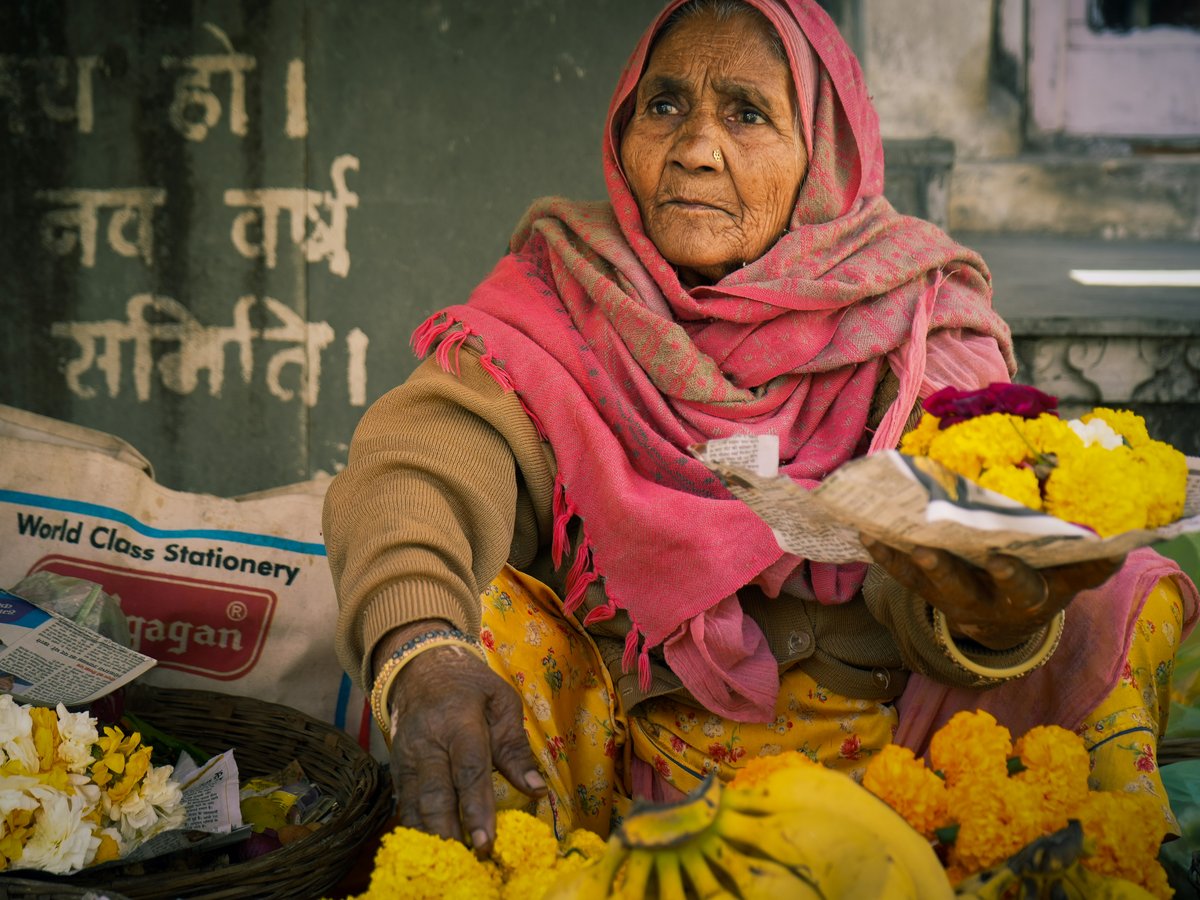 Elderly woman selling flowers and fruit